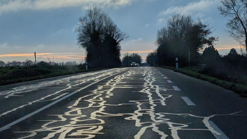Une route avec des "serpentins" de bitume qui dessinent de l'art routier
