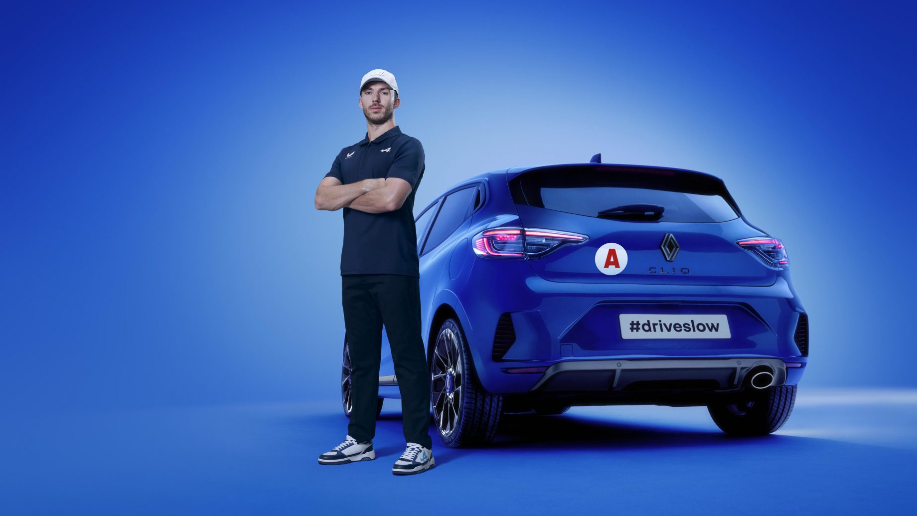 Le pilote Alpine F1, Pierre Gasly à côté d'une Clio avec le slogan #DriveSlow