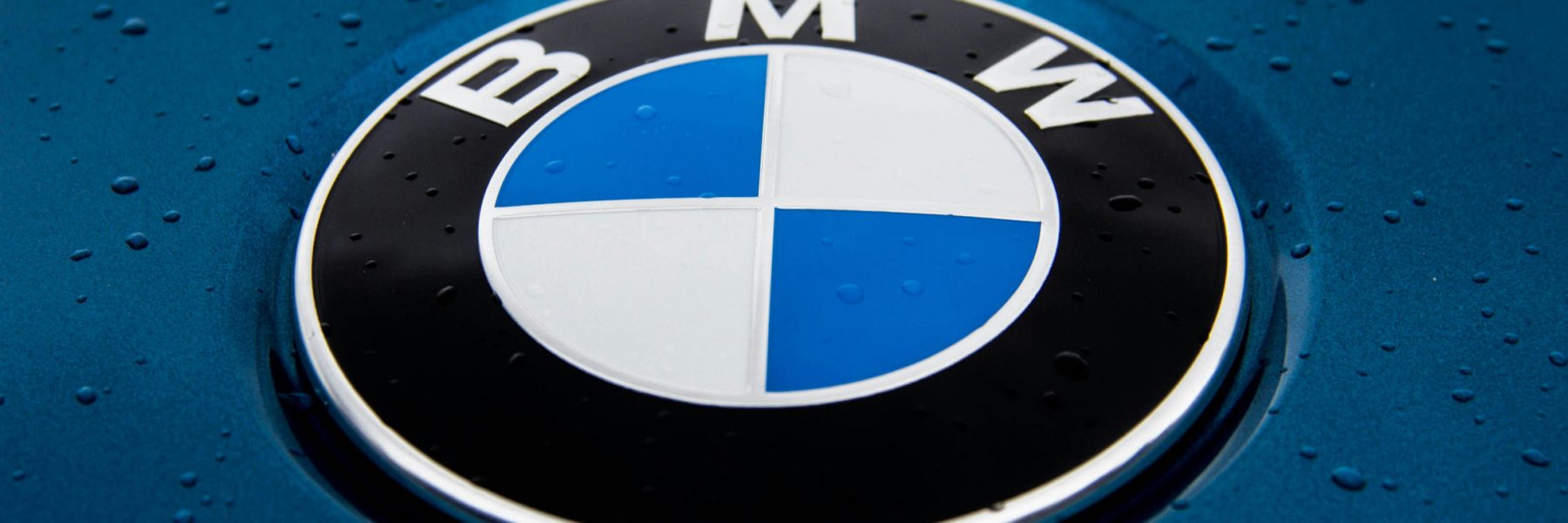 Le logo BMW sur un capot, avec quelques gouttes de pluie.