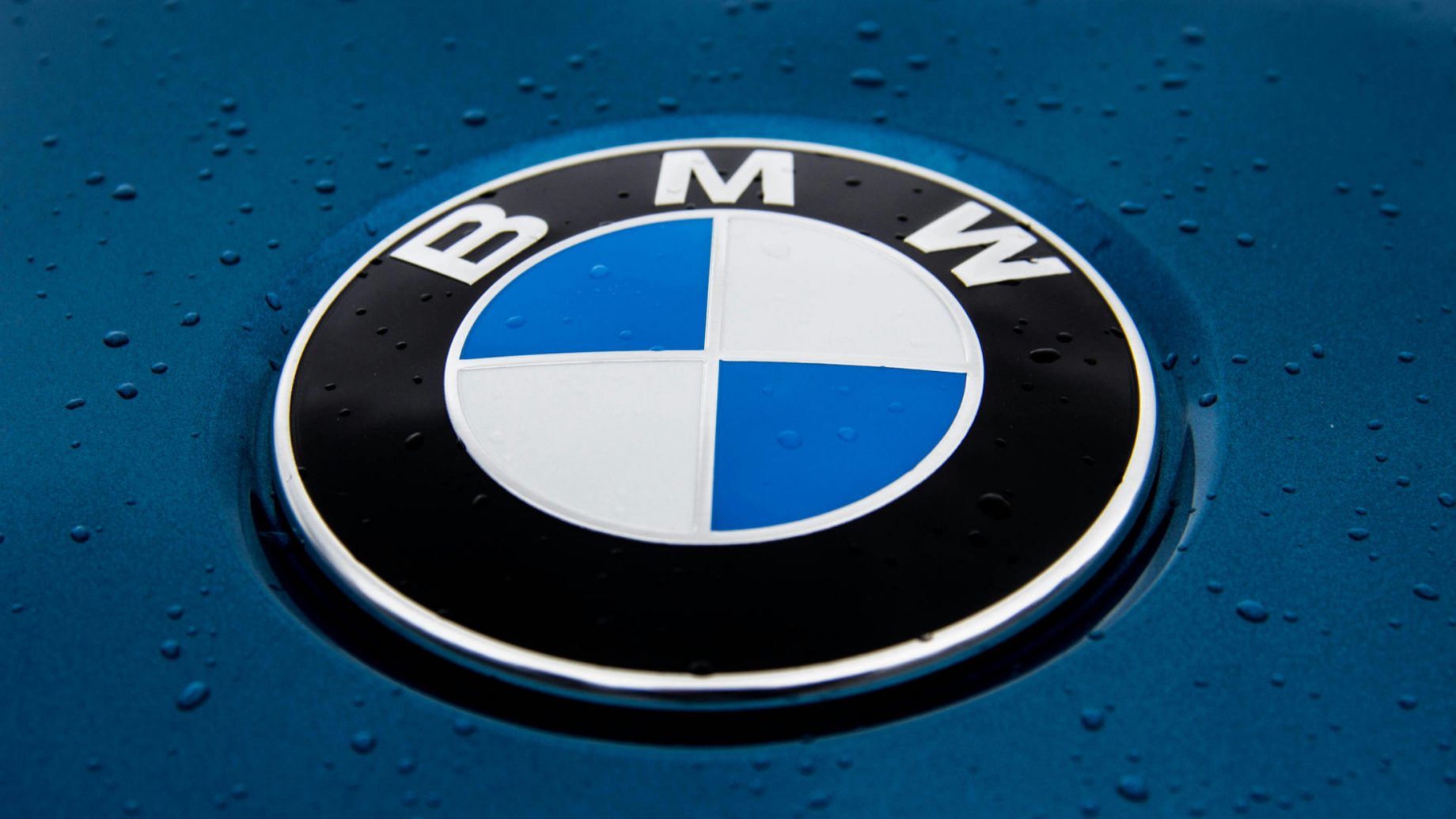 Le logo BMW sur un capot, avec quelques gouttes de pluie.